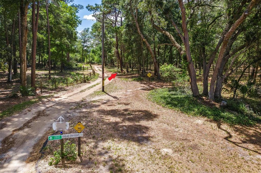 A dirt driveway leads into a wooded area with a signpost in the foreground — SE 152ND - LOT 17 (RAVENSWOOD RD) PARCEL C PLACE, ALTOONA, FL