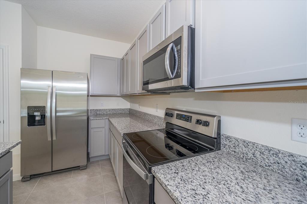 A kitchen featuring gray cabinets, granite countertops, and stainless steel appliances — 16642 MAUDE DRIVE, WIMAUMA, FL