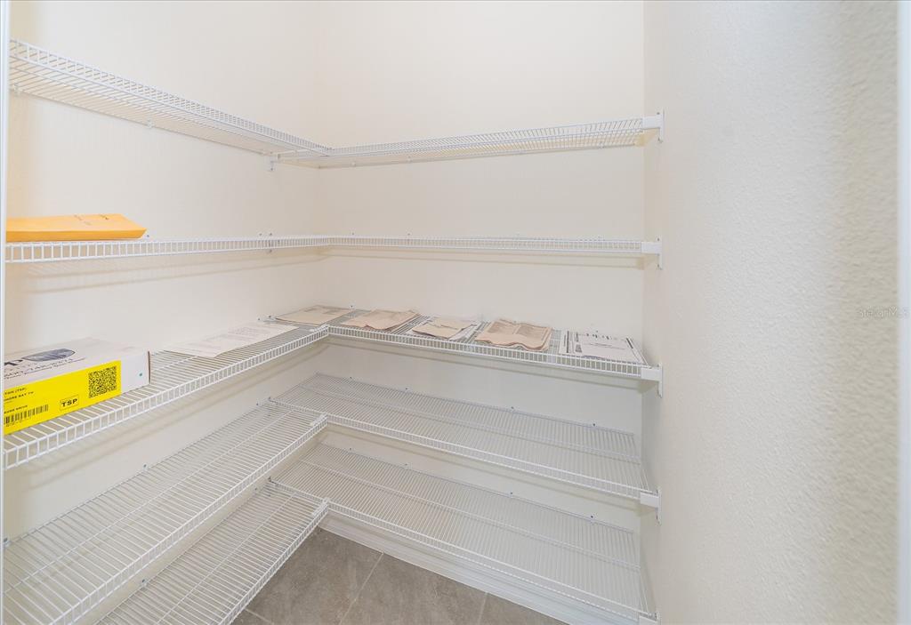 A walk-in pantry features white wire shelving installed along the walls over tiled flooring — 16642 MAUDE DRIVE, WIMAUMA, FL