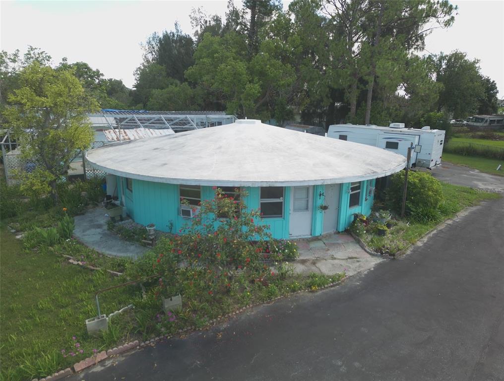 An aerial view of a round, turquoise-colored house with a large, flat, circular roof — 1603 W SHELL POINT ROAD, RUSKIN, FL