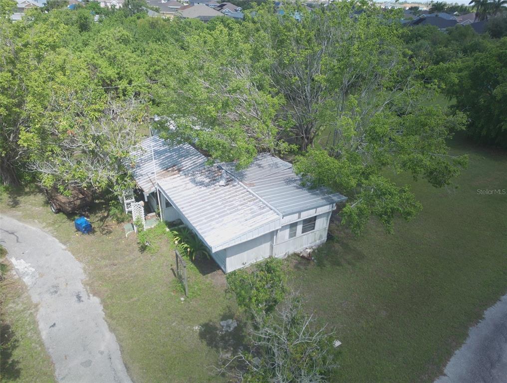 An aerial view shows a small, weathered house with a metal roof surrounded by trees — 1603 W SHELL POINT ROAD, RUSKIN, FL