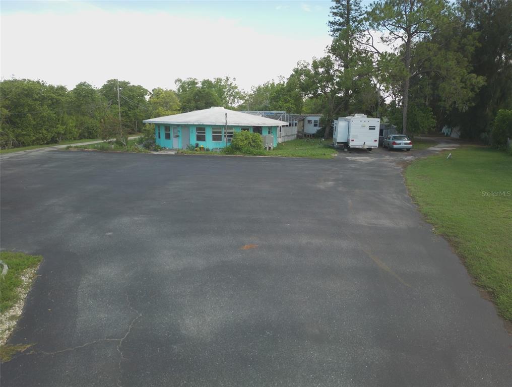 An aerial view shows a turquoise house with a large asphalt driveway and a trailer — 1603 W SHELL POINT ROAD, RUSKIN, FL
