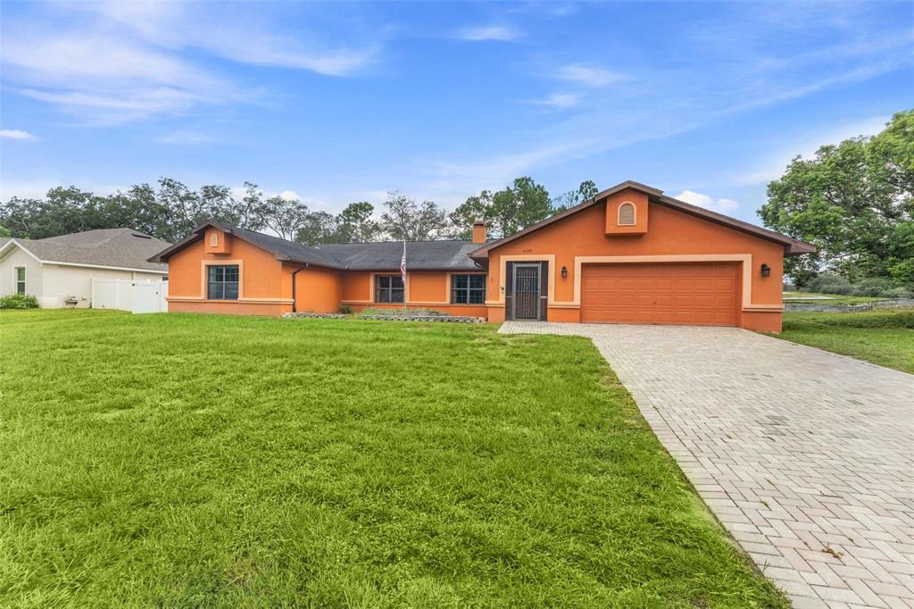 A single-story orange house with a two-car garage and a paved driveway — 4289 CASTLE AVENUE, SPRING HILL, FL