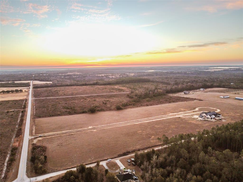 An aerial view shows a large, cleared plot of land with a house under construction — 4240 ROYAL SKY (LOT 6) COURT, BROOKSVILLE, FL