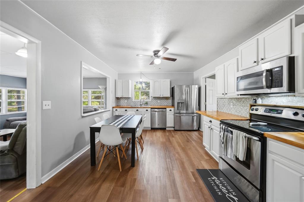 A kitchen features white cabinets, stainless steel appliances, wood countertops, and an adjacent dining area — 2403 SE POINTER AVENUE, ARCADIA, FL