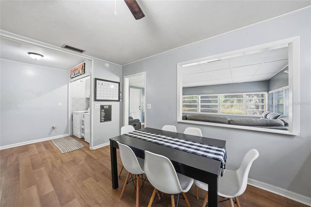 A dining area with a black table, white chairs, and a large window looking into another room — 2403 SE POINTER AVENUE, ARCADIA, FL