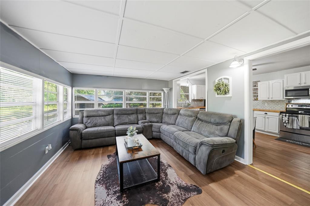 A living room features a gray sectional sofa, a wood coffee table, and wood-look flooring — 2403 SE POINTER AVENUE, ARCADIA, FL