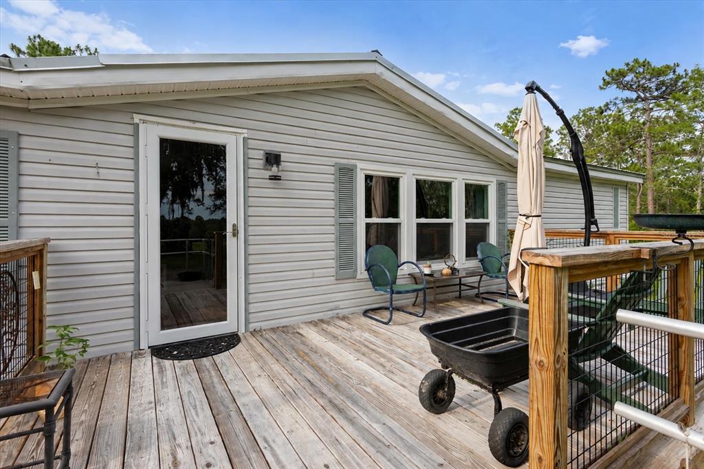 A wooden deck with a black utility cart sits outside a house with gray siding — 7220 NE 24TH LOOP, HIGH SPRINGS, FL