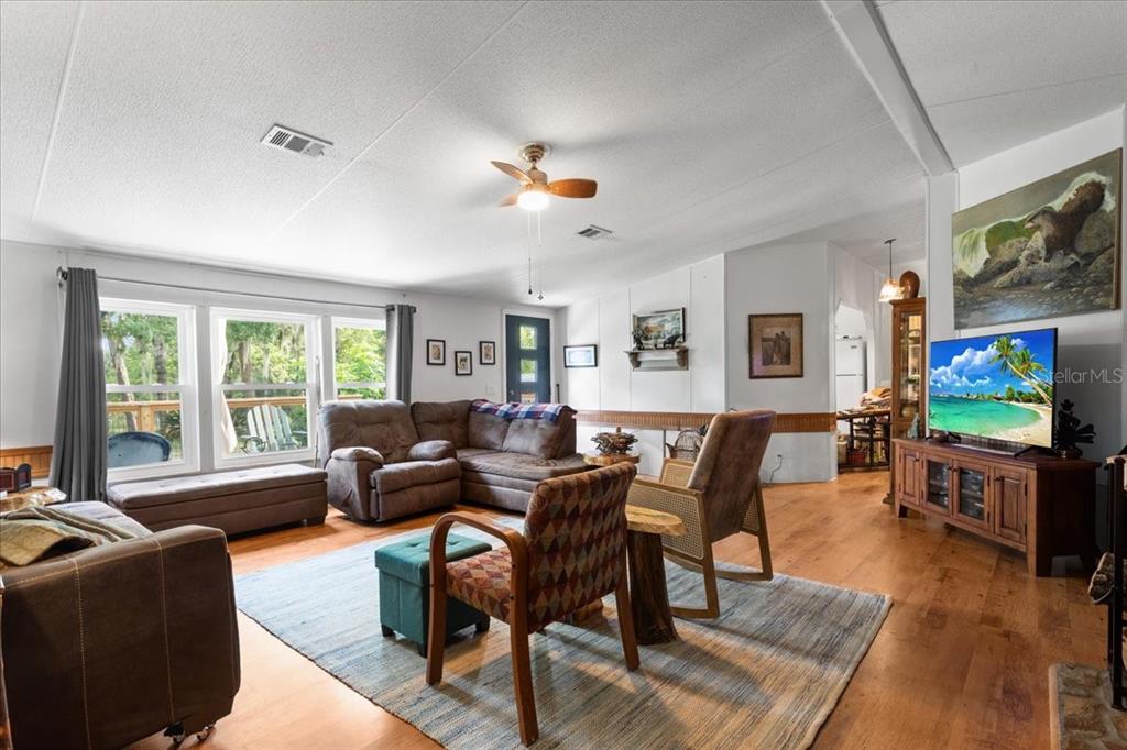 A living room features wood flooring, a sectional sofa, armchairs, and a television on a console — 7220 NE 24TH LOOP, HIGH SPRINGS, FL