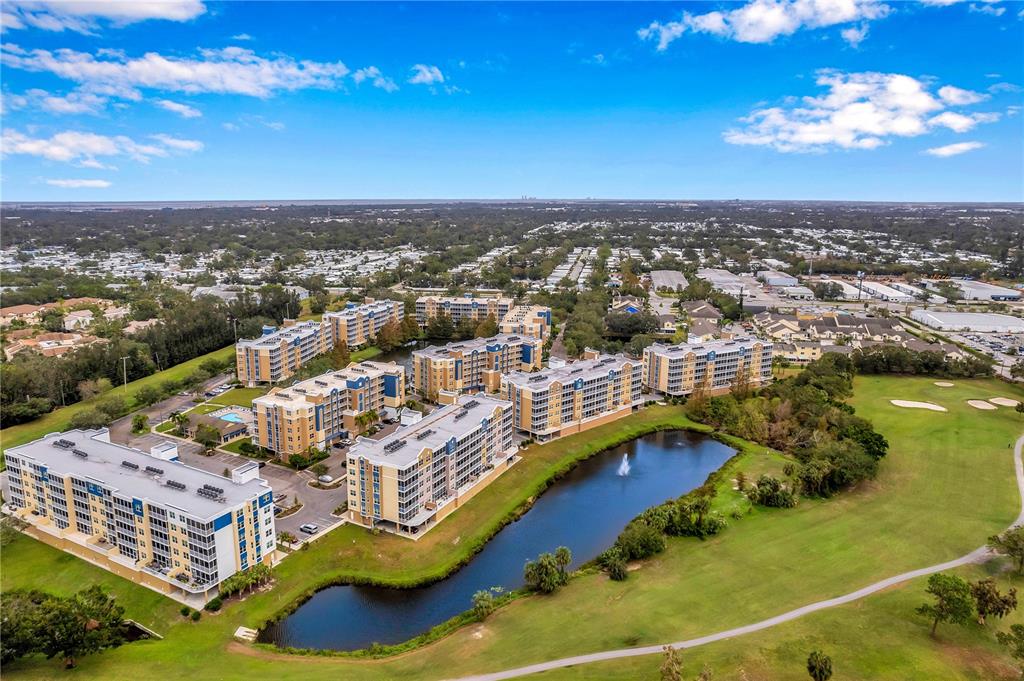 An aerial view shows a multi-story apartment complex situated next to a pond and golf course — 960 STARKEY ROAD UNIT 7205, LARGO, FL