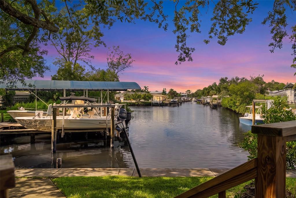 A boat docked at a canal lift with a sunset sky in the background — 2002 8TH STREET W, PALMETTO, FL
