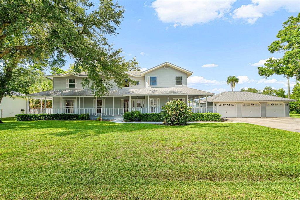 A two-story light gray house with a wrap-around porch and a detached three-car garage — 2002 8TH STREET W, PALMETTO, FL