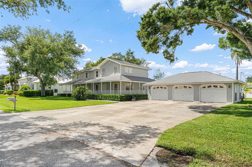 A two-story light gray house with a wrap-around porch and a detached three-car garage — 2002 8TH STREET W, PALMETTO, FL