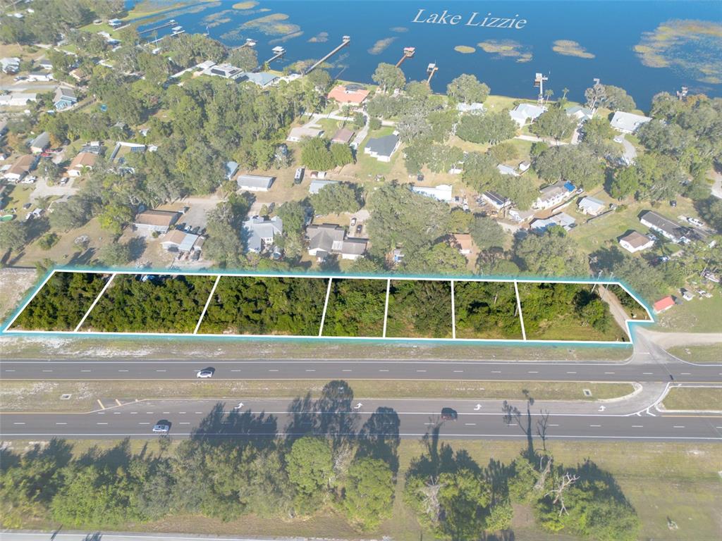 An aerial view shows a row of six vacant, wooded lots bordering a multi-lane highway — E IRLO BRONSON MEMORIAL HIGHWAY UNIT 0270, ST CLOUD, FL