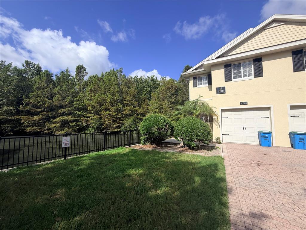 A two-story townhouse exterior with a garage, a small lawn, and a black metal fence — 10703 REGENT SQUARE DRIVE UNIT 1801, ORLANDO, FL