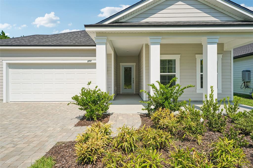 A single-story house exterior features light siding, a white garage door, and a covered porch — 272 SILVER LILY WAY, ST AUGUSTINE, FL