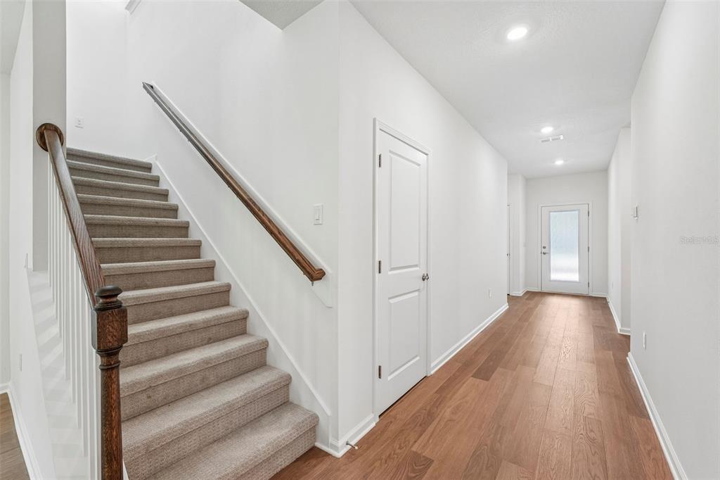 An interior hallway features a carpeted staircase with a wood railing and light wood flooring — 272 SILVER LILY WAY, ST AUGUSTINE, FL