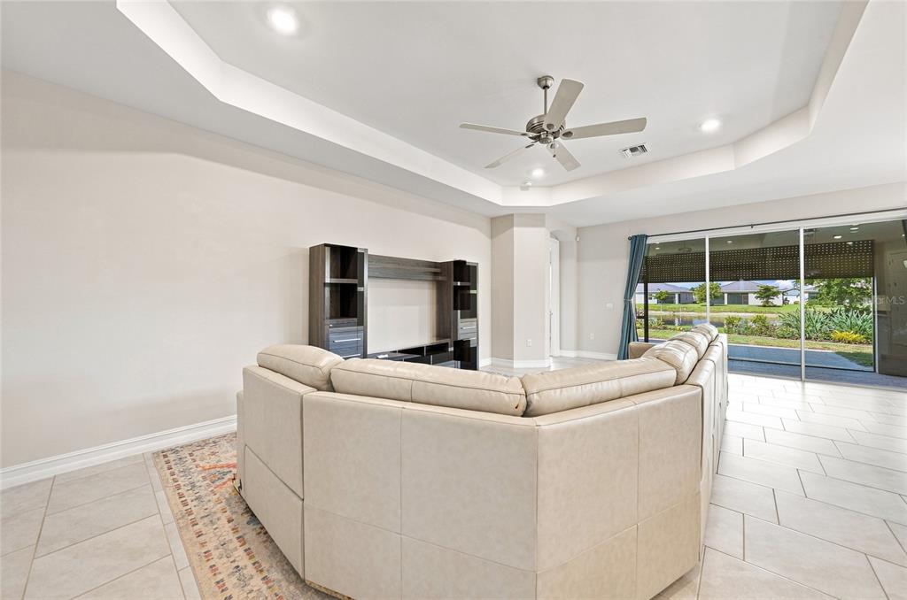 A living room features a large sectional sofa, a media console, and sliding glass doors — 719 HEATHER LAKE AVENUE, CAPE CORAL, FL