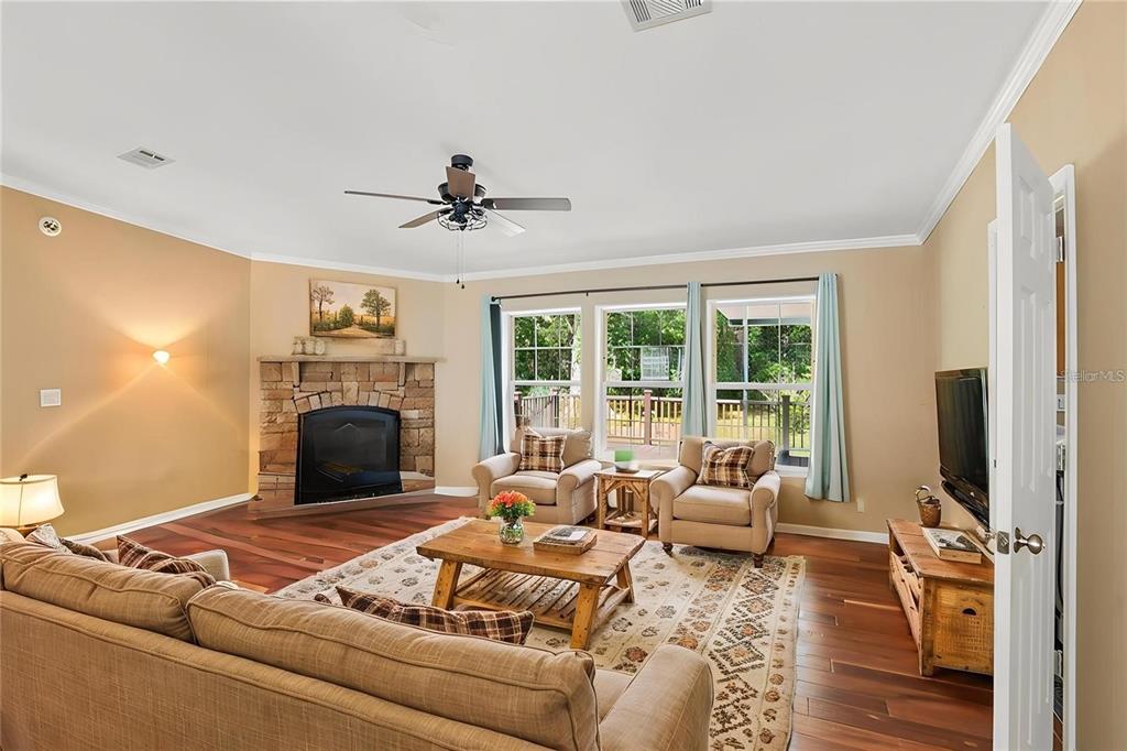 A living room features a stone fireplace, hardwood floors, two armchairs, and a large sofa — 6221 EMERSON ROAD, BROOKSVILLE, FL