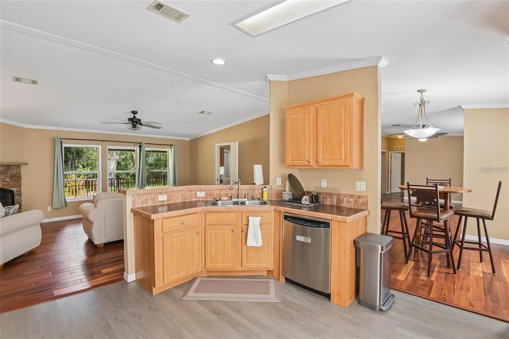A kitchen with light wood cabinets, a stainless steel dishwasher, and a tiled backsplash — 6221 EMERSON ROAD, BROOKSVILLE, FL