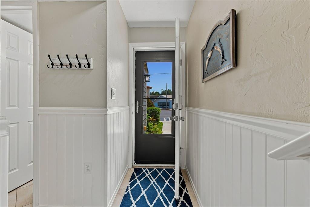 An entryway features white wainscoting, a coat rack, a blue patterned rug, and a glass door — 65 BEACH LANE UNIT N, CRYSTAL RIVER, FL