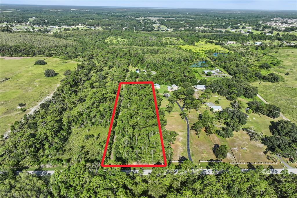 An aerial view shows a rectangular wooded lot outlined in red along a paved road — 0 LAKE GENTRY ROAD, ST CLOUD, FL