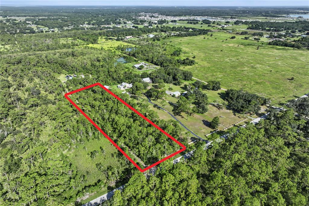 An aerial view shows a rectangular plot of land outlined in red amidst wooded terrain — 0 LAKE GENTRY ROAD, ST CLOUD, FL