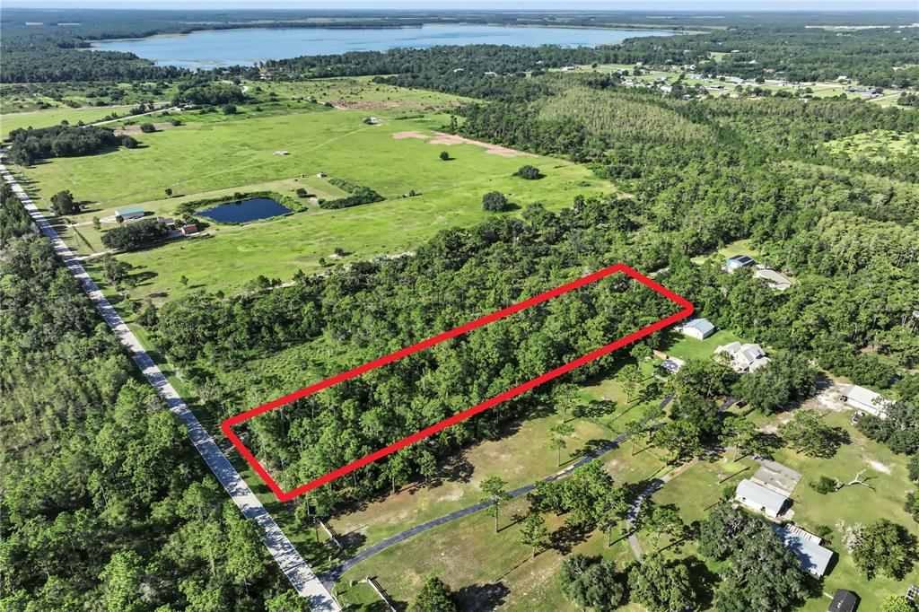 An aerial view shows a rectangular wooded lot outlined in red next to a road — 0 LAKE GENTRY ROAD, ST CLOUD, FL