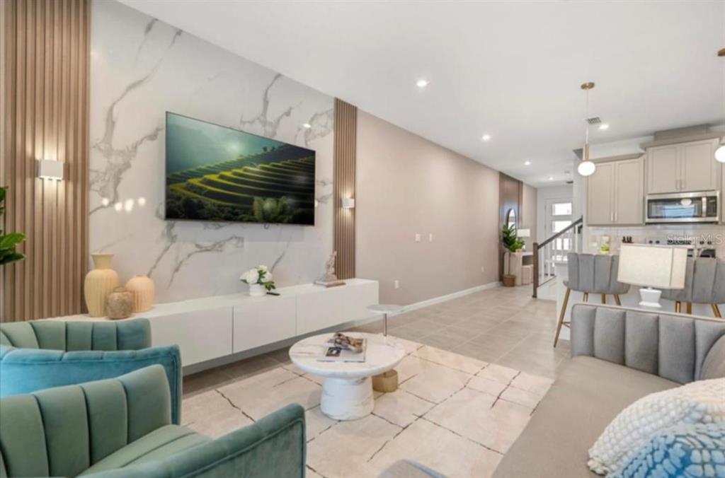 A living room features a marble accent wall with a television, wood slats, and furniture — 2381 DISTANT SUN TRAIL, KISSIMMEE, FL