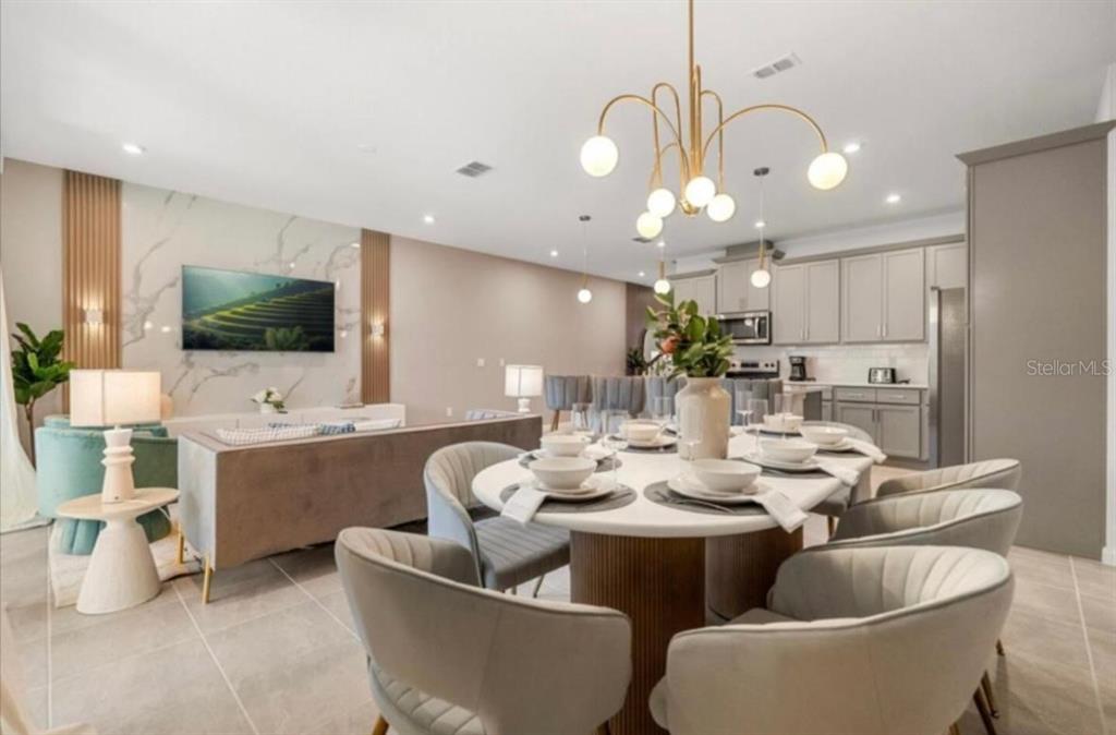An open-concept living and dining area features a marble accent wall and modern light fixtures — 2381 DISTANT SUN TRAIL, KISSIMMEE, FL