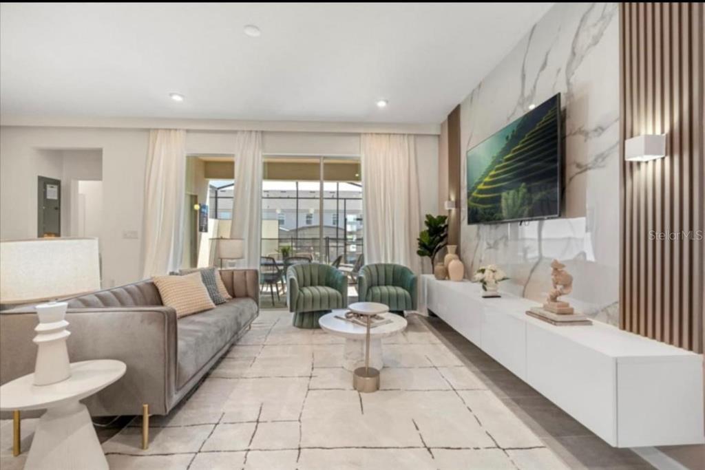A modern living room features a marble accent wall, floating console, and gray velvet sofa — 2381 DISTANT SUN TRAIL, KISSIMMEE, FL