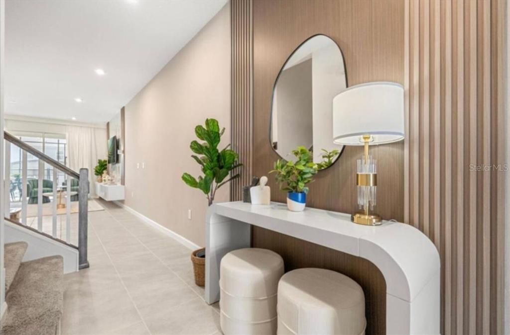 A modern entryway features a white console table, two stools, a mirror, and wood-slatted walls — 2381 DISTANT SUN TRAIL, KISSIMMEE, FL