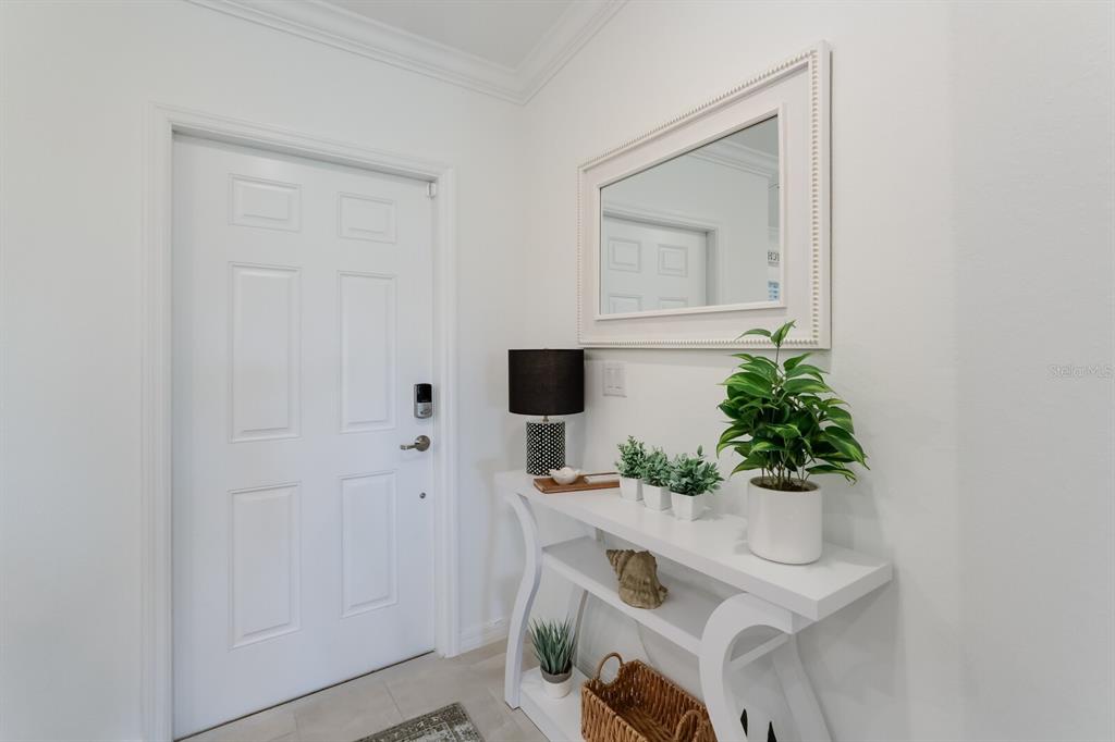 A white entryway features a console table, a mirror, and a door with a smart lock — 5721 PALMER CIRCLE UNIT 201, BRADENTON, FL