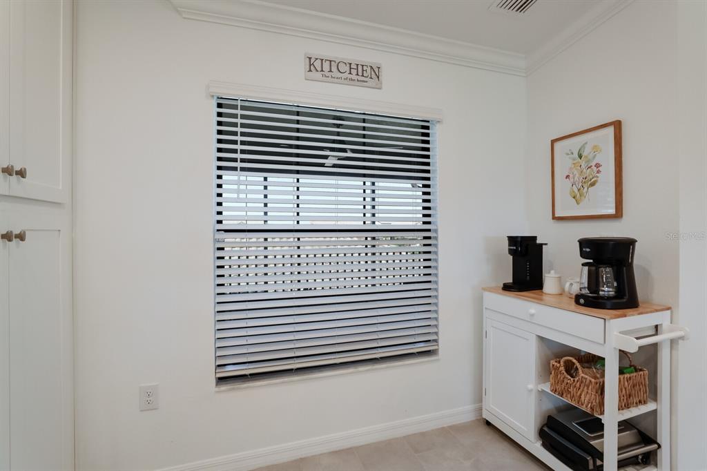 A kitchen corner features a window with blinds, a coffee station, and a wall sign — 5721 PALMER CIRCLE UNIT 201, BRADENTON, FL