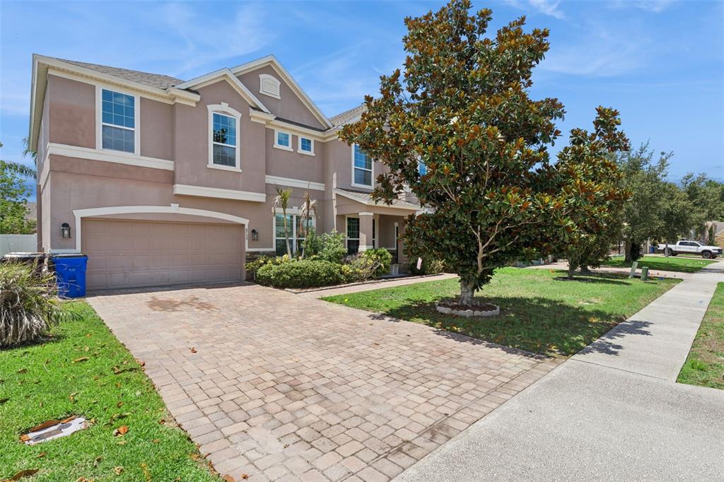 A two-story house with a paved driveway, a two-car garage, and a large front tree — 4750 CYPRESS FOREST LANE, ST CLOUD, FL