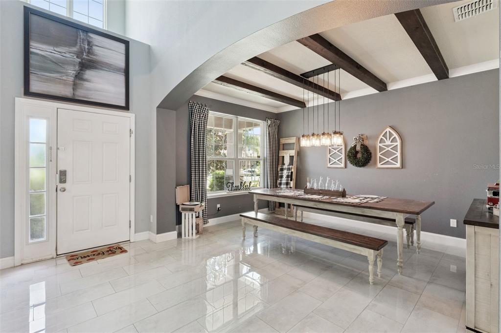 A dining area with a long wooden table, benches, and exposed ceiling beams — 4750 CYPRESS FOREST LANE, ST CLOUD, FL