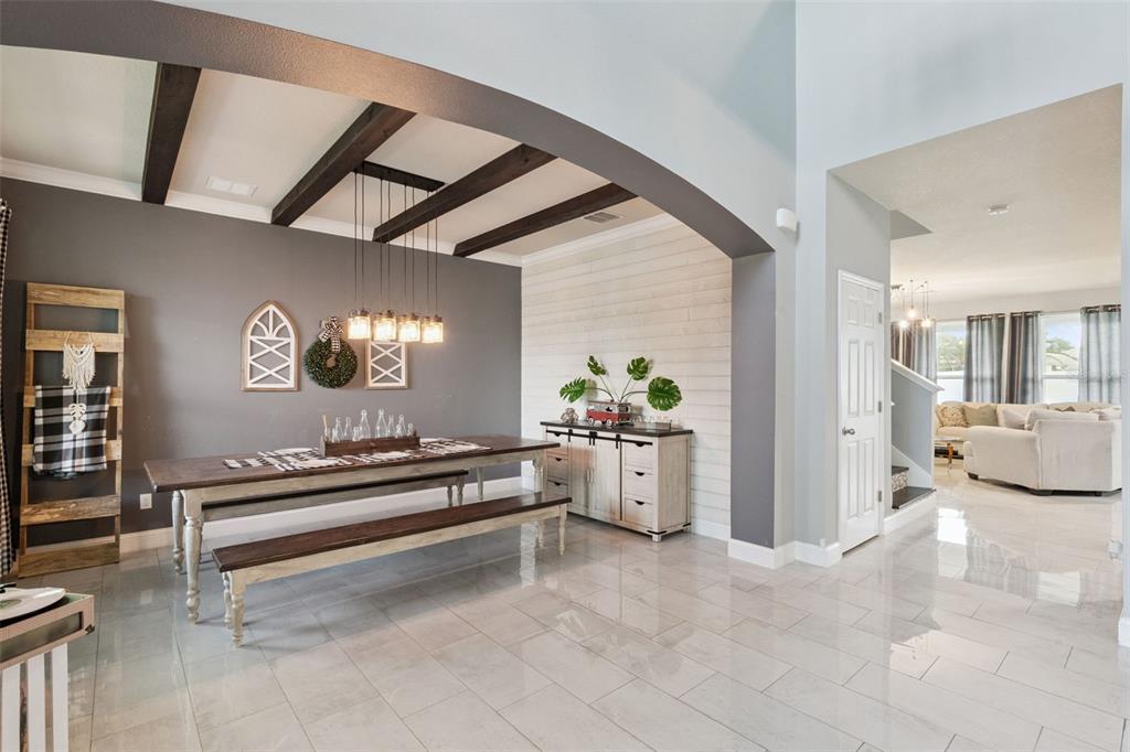 A dining room features a wooden table, bench seating, and a shiplap accent wall — 4750 CYPRESS FOREST LANE, ST CLOUD, FL