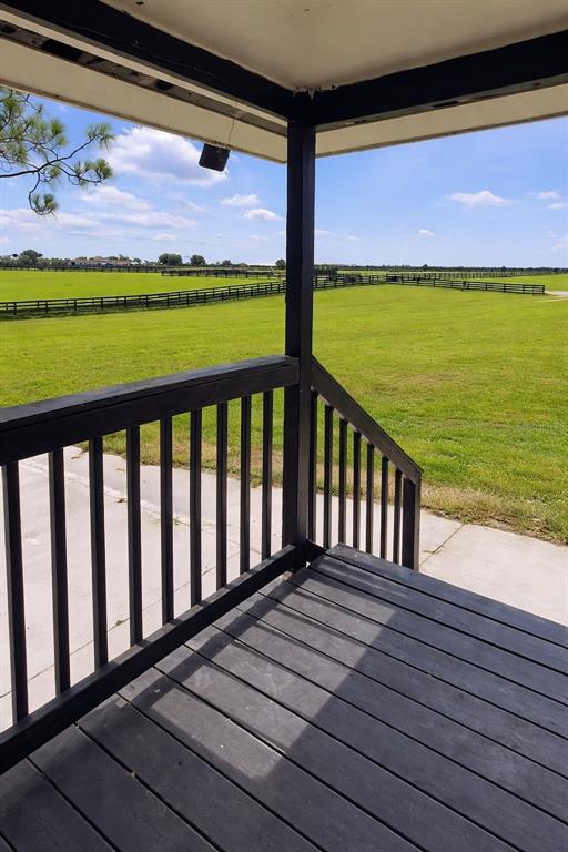 A view from a covered wooden porch overlooking a large, fenced grassy field — 12451 NE 20TH STREET, WILLISTON, FL