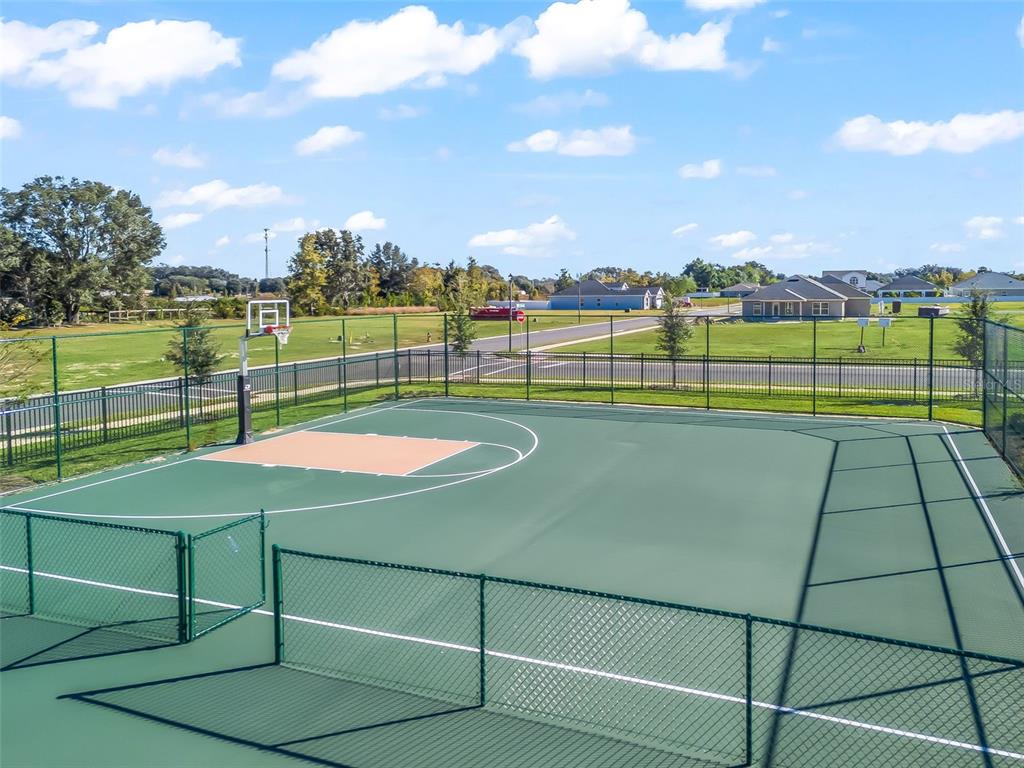 An outdoor basketball court enclosed by a chain-link fence under a blue sky — NE 125TH LOOP, PHASE 3, OXFORD, FL