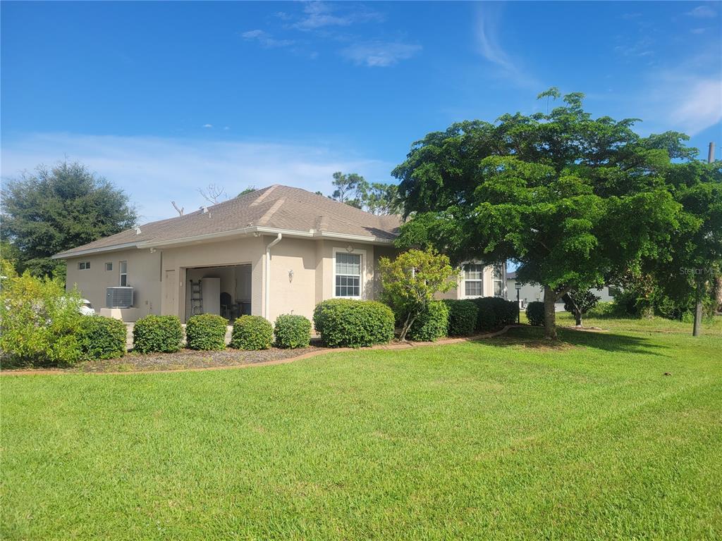 A beige single-story house with a two-car garage and a large tree in the yard — 12 TEE VIEW COURT, ROTONDA WEST, FL