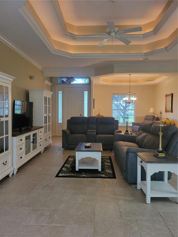 A living room features a tray ceiling, tile flooring, white cabinetry, and grey reclining furniture — 12 TEE VIEW COURT, ROTONDA WEST, FL