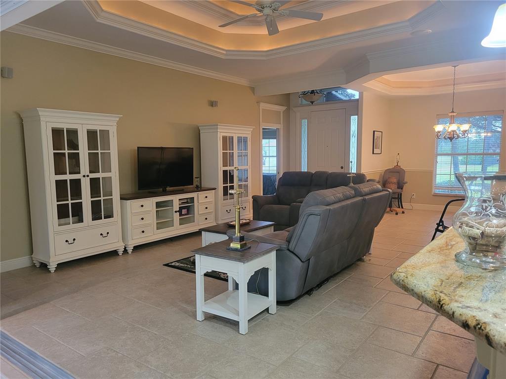 A living room features a grey reclining sofa, white cabinetry, and tile flooring — 12 TEE VIEW COURT, ROTONDA WEST, FL