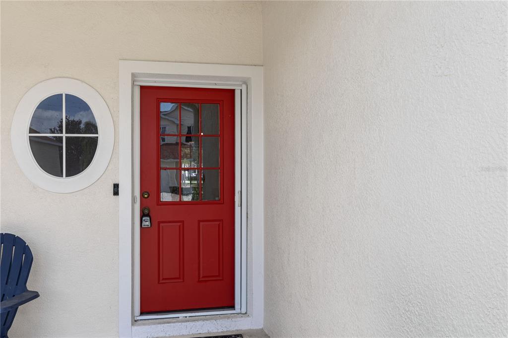 A red front door with a glass window sits next to a circular window — 1073 JONAH DRIVE, NORTH PORT, FL
