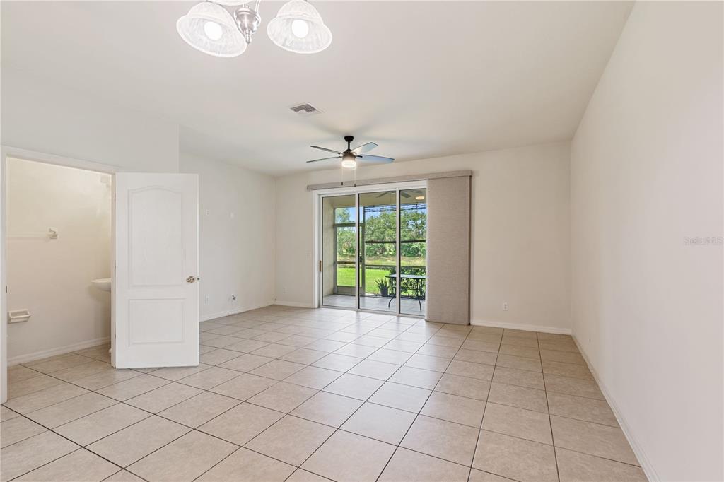 A tiled room features a ceiling fan, a light fixture, and sliding doors to a patio — 1073 JONAH DRIVE, NORTH PORT, FL