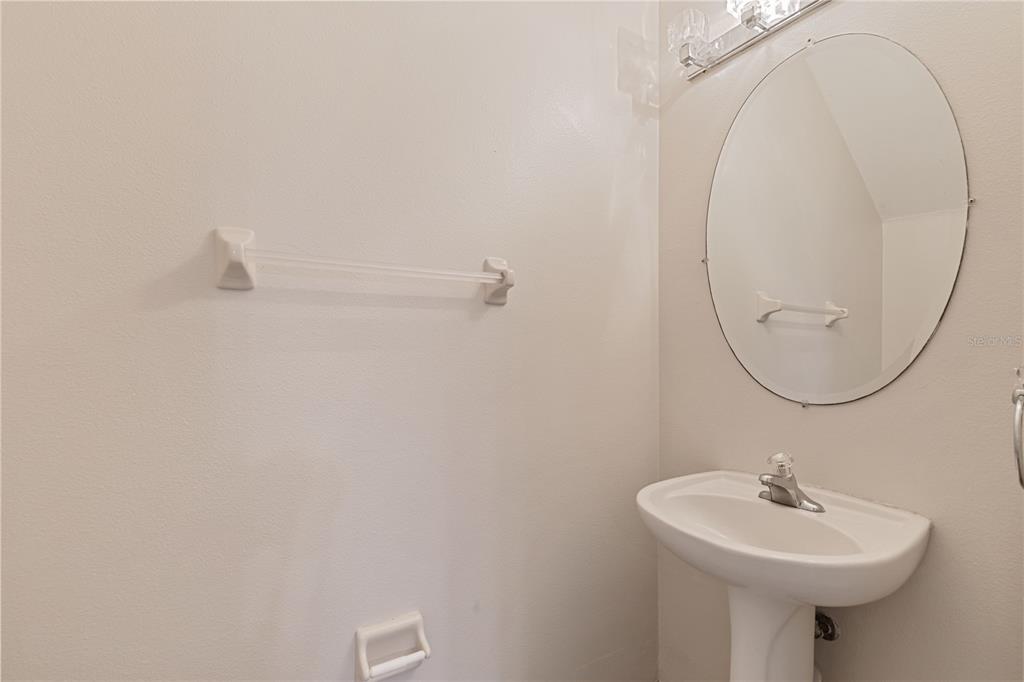 A small bathroom features a pedestal sink, an oval mirror, and a wall-mounted towel bar — 1073 JONAH DRIVE, NORTH PORT, FL