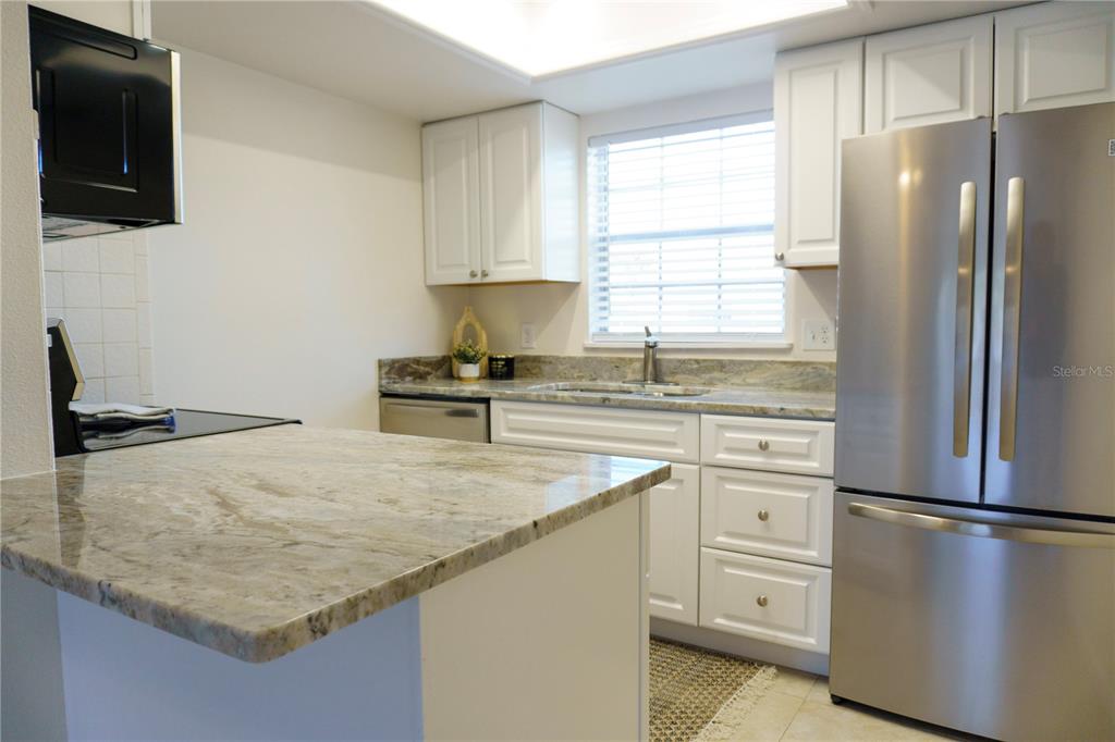 A kitchen features white cabinets, granite countertops, and stainless steel appliances — 4725 AVON COURT, ST CLOUD, FL