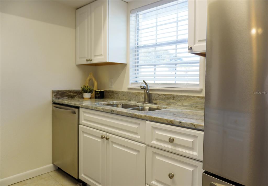 A kitchen features white cabinets, granite countertops, a stainless steel dishwasher, and a window — 4725 AVON COURT, ST CLOUD, FL