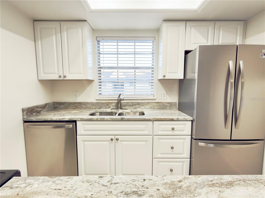 A kitchen features white cabinets, stainless steel appliances, and a marble-patterned countertop — 4725 AVON COURT, ST CLOUD, FL