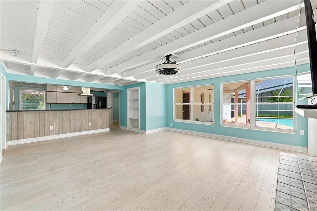 A bright living room with light wood floors, white beamed ceilings, and a kitchen bar — 1361 PINELLAS ROAD, CLEARWATER, FL