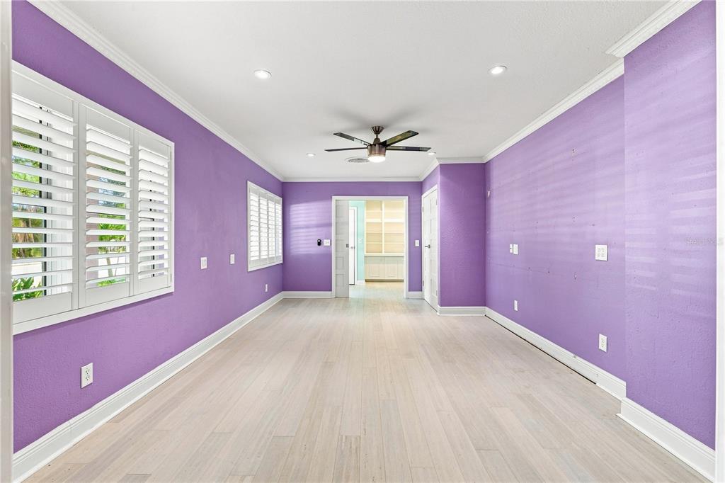 A room with purple walls, light wood flooring, a ceiling fan, and white plantation shutters — 1361 PINELLAS ROAD, CLEARWATER, FL